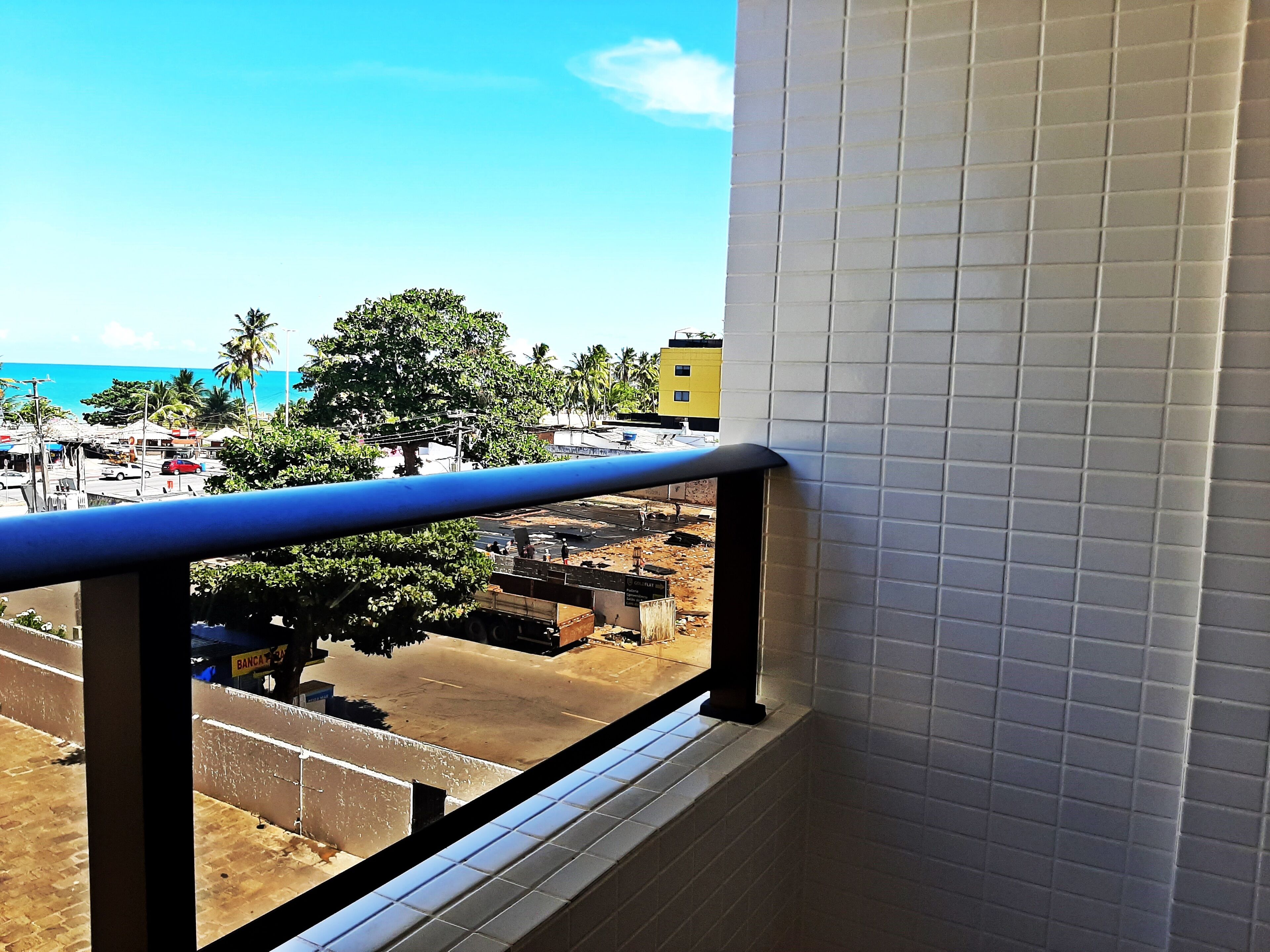A view from a window with white tiled walls and a blue railing.