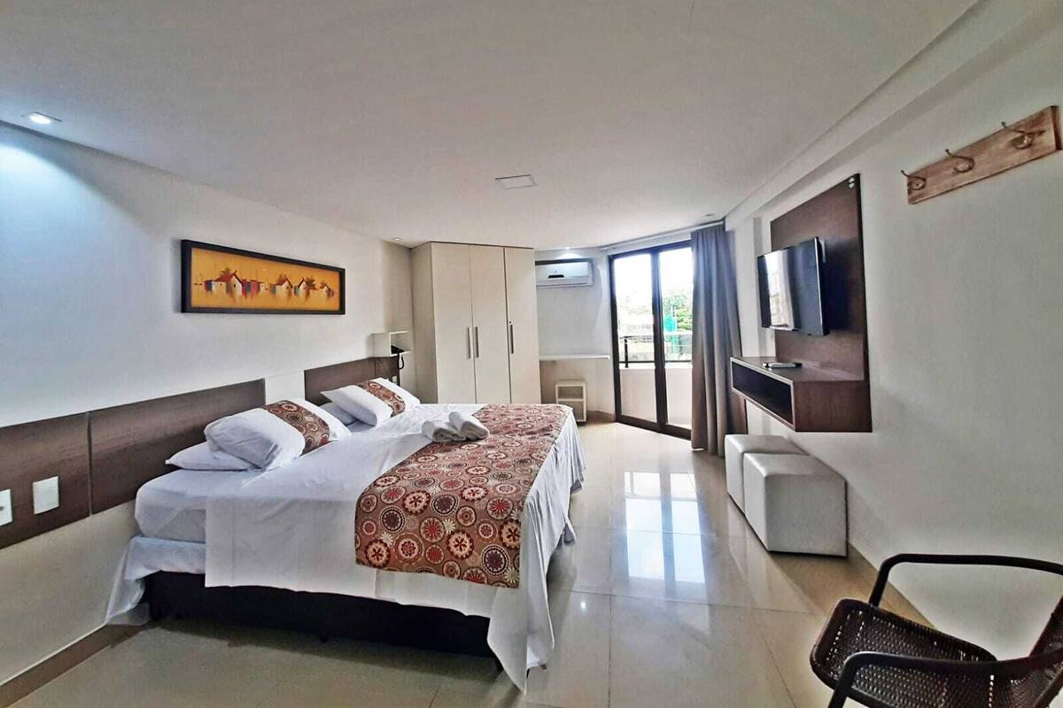 Habitación de hotel con una cama grande, un televisor, un escritorio y una silla.