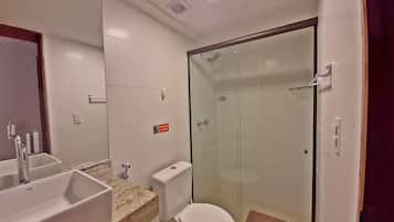 A bathroom with a glass-enclosed shower, a sink with a marble countertop, and a toilet.