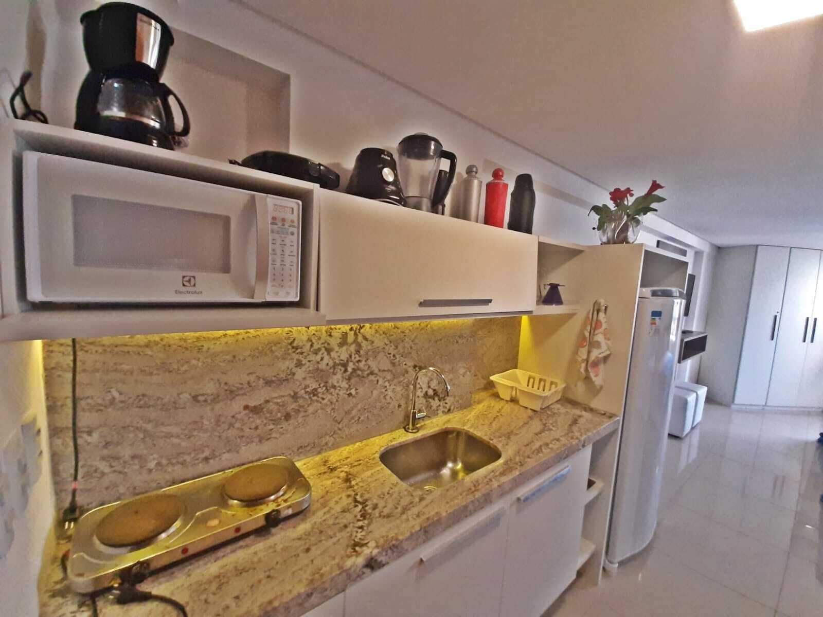 Una cocina equipada con microondas, cafetera y lavabo.