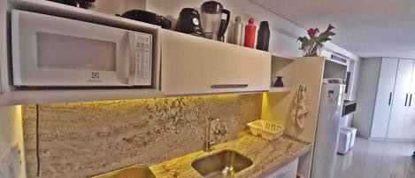 Una cocina equipada con microondas, cafetera y lavabo.