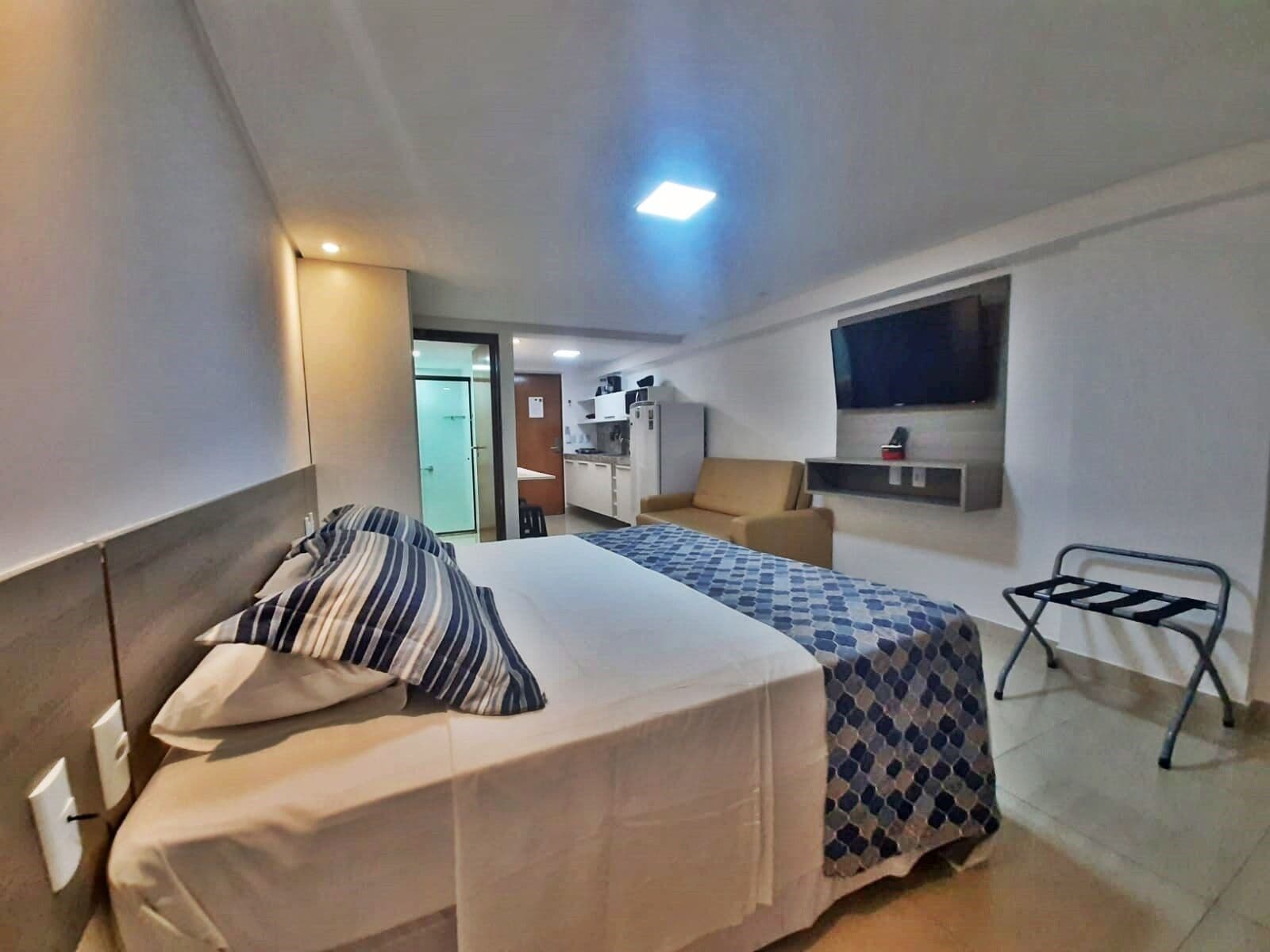 Una habitación de hotel con cama, sofá, televisión y kitchenette.
