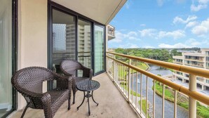Ein Balkon mit Korbmöbeln und Blick auf einen Fluss und Gebäude.