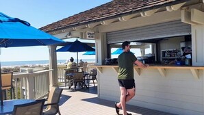 Eine Barbereich mit Theke, Sitzgelegenheiten im Freien und Blick auf den Strand.