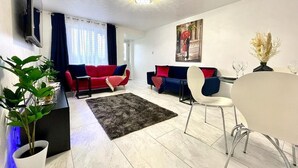 Un salon moderne avec deux canapés, une table à manger et un téléviseur fixé au mur.