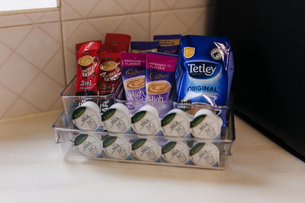 Una encimera de cocina con una variedad de productos de café y té, incluyendo las marcas Tetraxy y Cadbury.