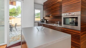 A modern kitchen with a large island, stainless steel appliances, and wooden paneling. - 3 bedroom awesome apartment in Rab (Rab)