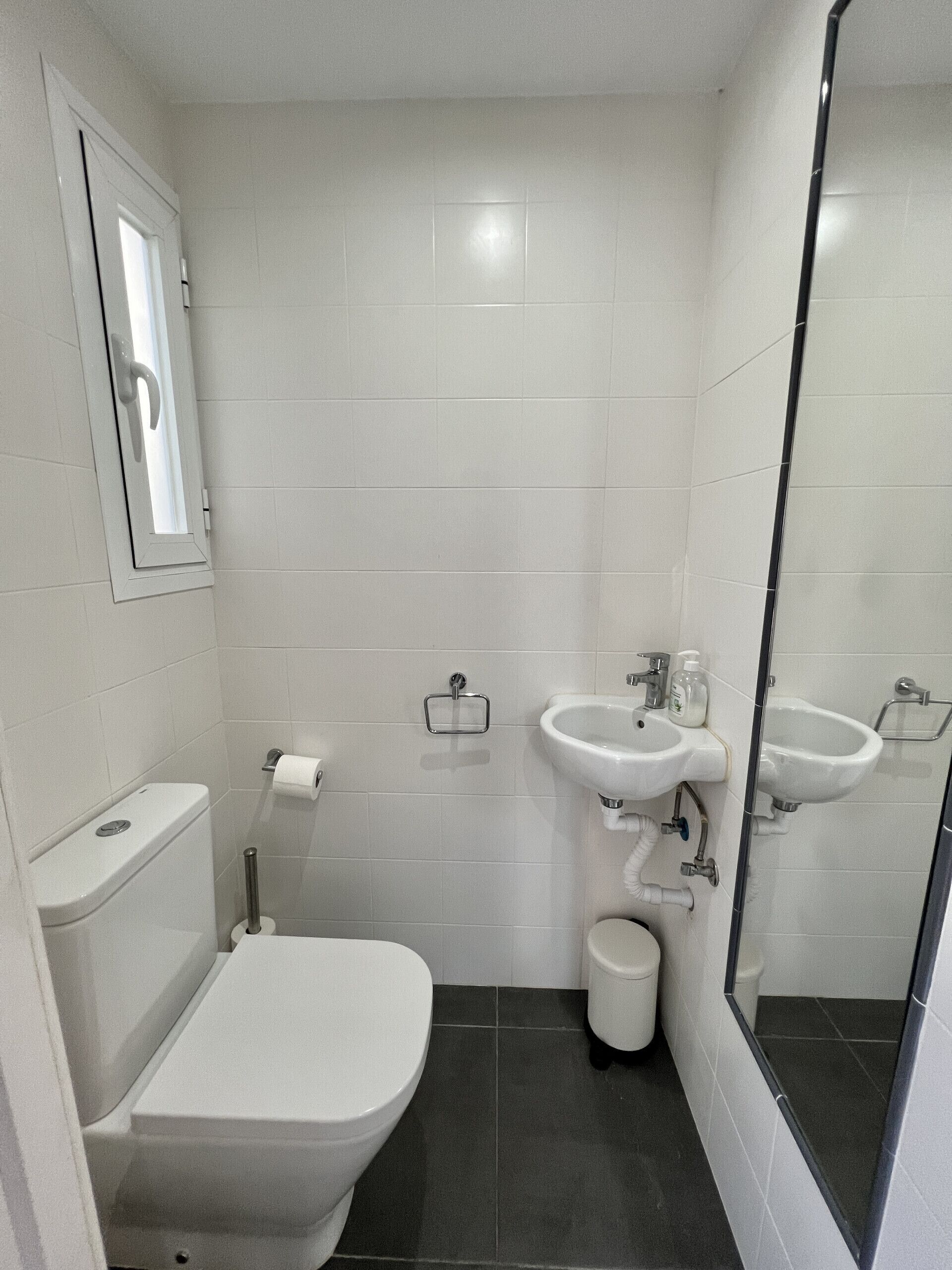 A compact bathroom with a toilet, bidet, and two sinks.
