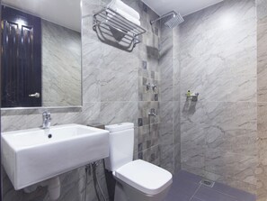 Casa de banho moderna com lavatório, sanita e chuveiro, tudo em branco.