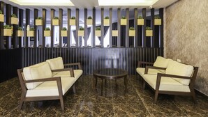 A modern lobby with two sofas and a round table, a decorative wall with vertical panels, and a marble floor. - Hotel Midaris Syariah Kuala Lumpur (Kuala Lumpur)