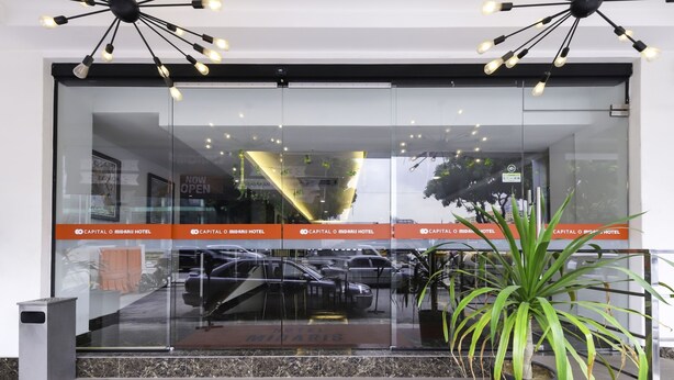 The entrance of the Capital O Midaris Hotel with a modern glass facade, a black and white light fixture above the entrance, and a potted plant to the right. - Hotel Midaris Syariah Kuala Lumpur (Kuala Lumpur)