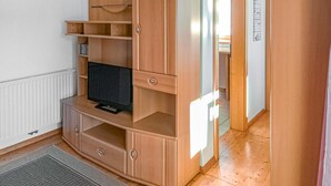 A compact living space with a built-in TV, wooden shelving, and a radiator.