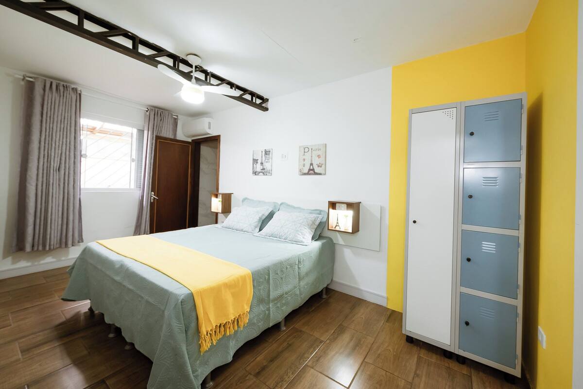 A bedroom with a bed, wooden flooring, a wardrobe, and wall-mounted lights.
