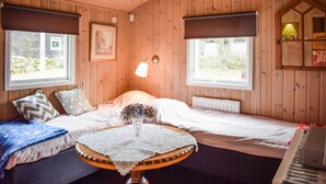 Ein gemütliches Zimmer mit einem Bett, einem kleinen Tisch mit Spitze und zwei Fenstern mit Jalousien.