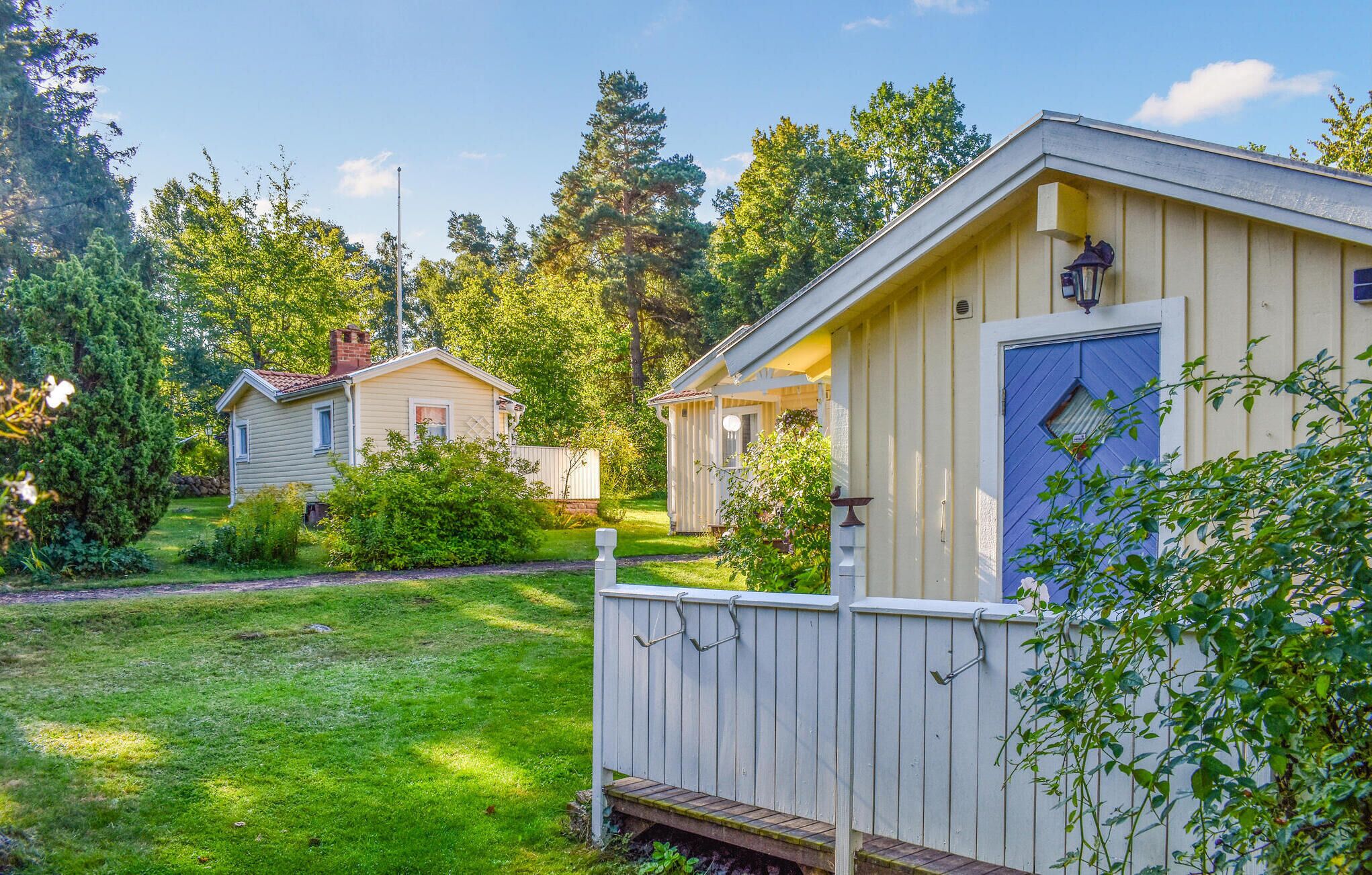 A row of cabins with a grassy yard and trees in the background.
