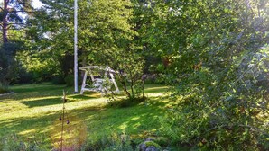 Ein Garten mit Schaukel, Rasen und verschiedenen Pflanzen.