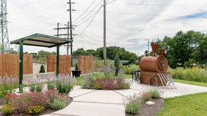 A garden with a pathway, a wooden fence, and a vintage train engine. - Mid Century Modern townhome in Historical Downtown Noblesville (Noblesville)