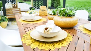 A wooden table set with white bowls and plates, yellow placemats, and potted plants. - Mid Century Modern townhome in Historical Downtown Noblesville (Noblesville)