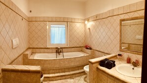 A bathroom with a freestanding bathtub, a sink, a toilet, and a window with a curtain. - The Attichetto (Ciampino)