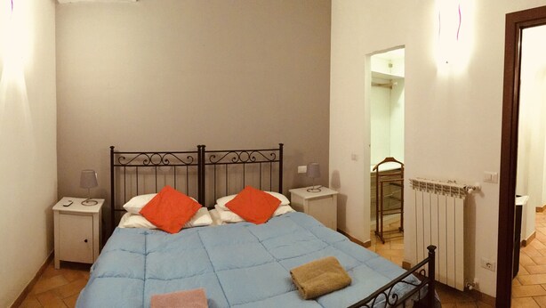 A bedroom with a bed, nightstands, a radiator, and a door. - The Attichetto (Ciampino)