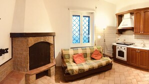 A compact kitchen with a built-in oven, wooden cabinets, and a small dining area with a table and chairs. - The Attichetto (Ciampino)
