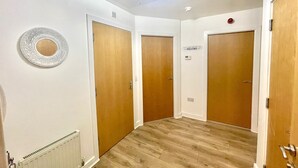 A hallway with three wooden doors, a radiator, and a decorative plate on the wall.