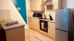A modern kitchen with wooden cabinets, a stainless steel refrigerator, a microwave, and a sink.