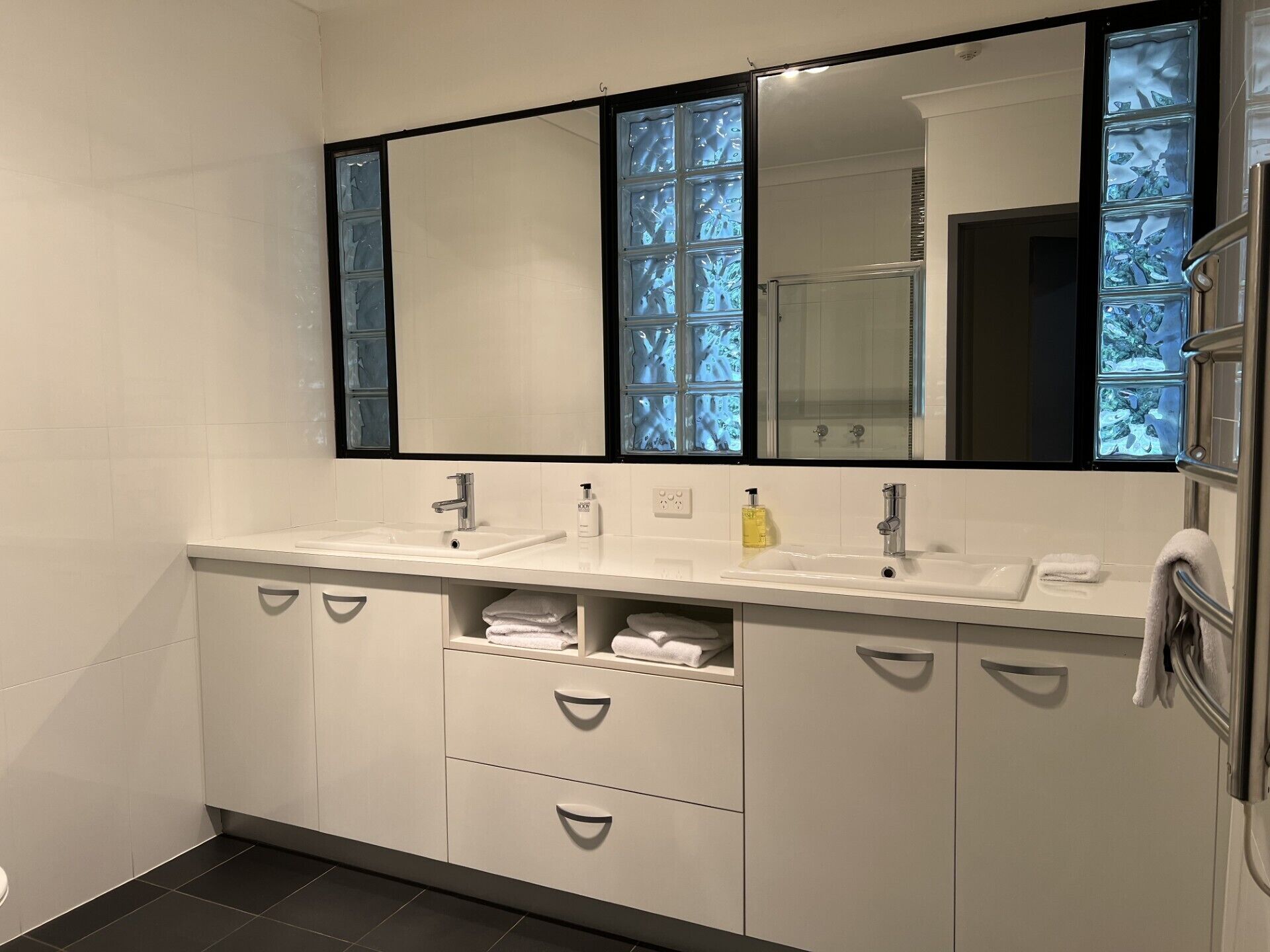 Une salle de bain moderne avec un grand miroir, deux lavabos et une douche.