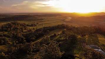 An aerial view of a landscape with fields, trees, and a small building.