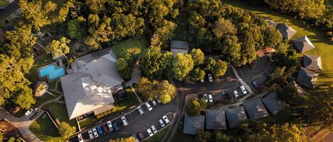 An aerial view of a residential area with houses, a swimming pool, and a parking lot.