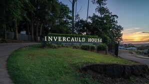 Eine angelegte Grünfläche mit einem Schild für Invercauld House, das darauf hinweist, dass Konferenzen, Retreats und Übernachtungen angeboten werden.