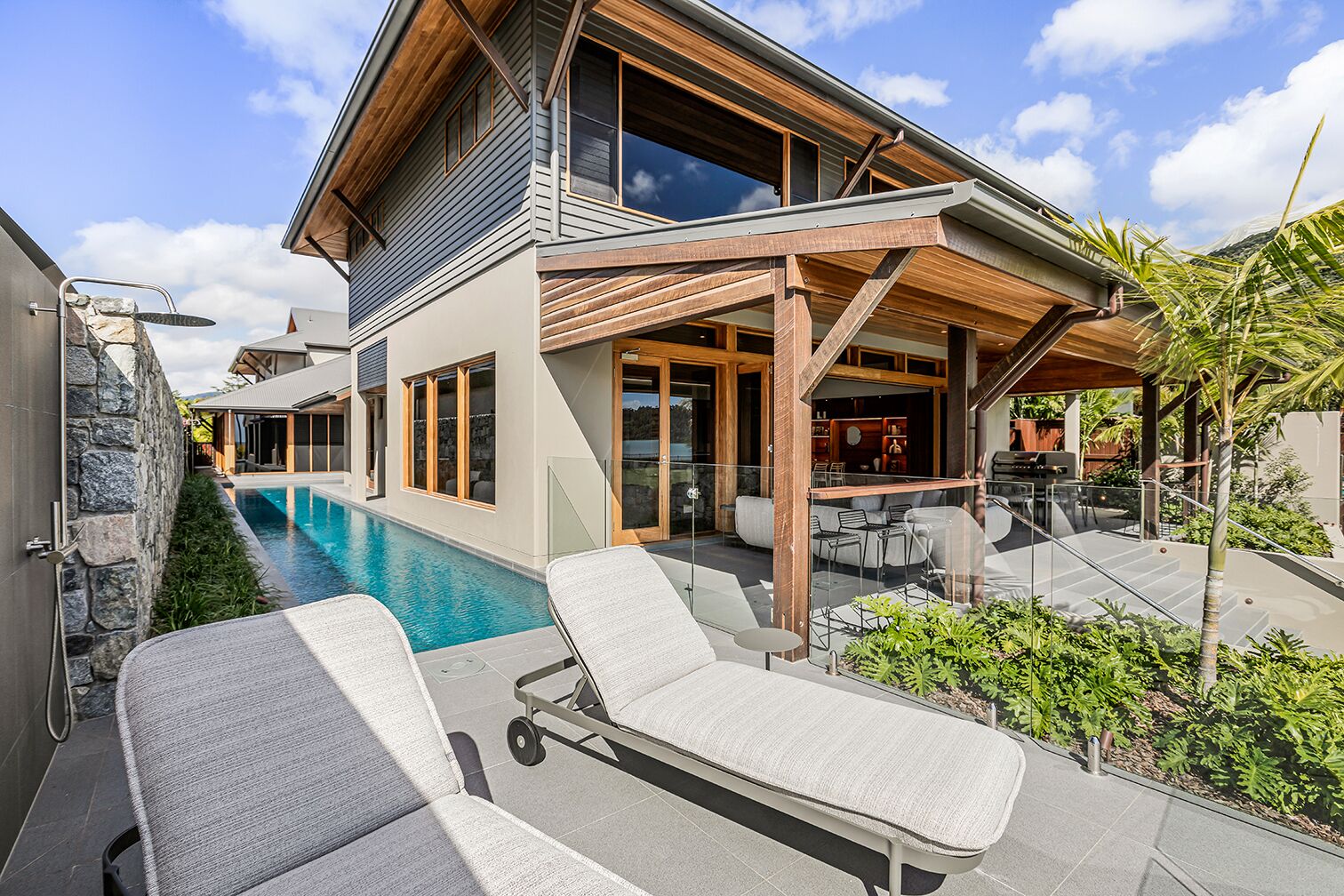 A modern house with a swimming pool, outdoor seating, and a covered patio area.