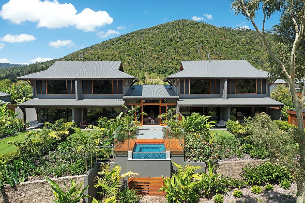 A modern two-story house with a swimming pool and lush garden.