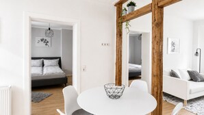 A modern, minimalist living space with a dining area, a sofa, a bed, and a large mirror.