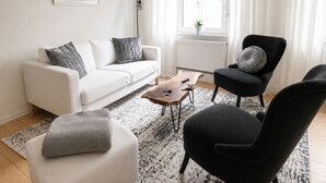 A modern living room with a white sofa, a black armchair, a coffee table, and a patterned rug.