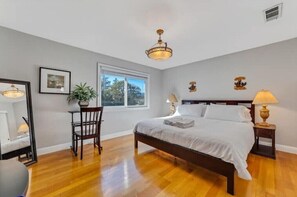 Relax in this serene bedroom with a large bed and a comfortable chair by the window.