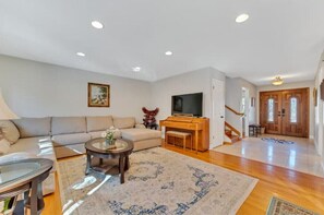Relax in this inviting living area with a sofa set, coffee table, and TV on a wooden stand.
