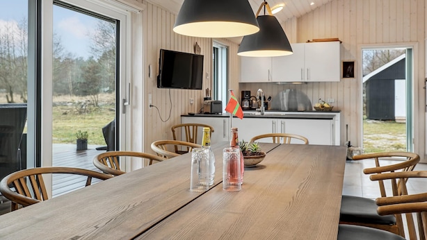 A dining area with a wooden table, chairs, and pendant lights. - 3 bedroom beautiful home in Aakirkeby (Aakirkeby)