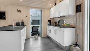 A modern kitchen with white cabinets, a black countertop, and a large window. - 3 bedroom beautiful home in Aakirkeby (Aakirkeby)