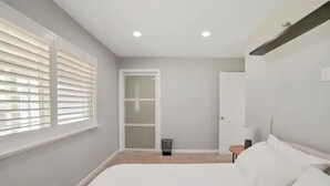 A bedroom with a bed, a small table, and a door leading to a balcony. - Beautiful, Stylish 3 Bedroom Home in San Jose! (San Jose)