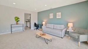 A modern living room with a grey sofa, a coffee table, and a dining area with a table and chairs. - Beautiful, Stylish 3 Bedroom Home in San Jose! (San Jose)