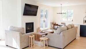 A modern living room with a fireplace, two sofas, a coffee table, and a TV mounted on the wall. - 4BR/2.5BA Home 3 Blocks to Beach (Half Moon Bay)