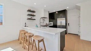 A modern kitchen with a central island, bar stools, and built-in appliances. - 4BR/2.5BA Home 3 Blocks to Beach (Half Moon Bay)