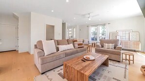 A spacious living room with two sofas, a coffee table, and a large window providing natural light. - 4BR/2.5BA Home 3 Blocks to Beach (Half Moon Bay)