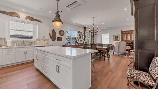 A spacious kitchen with a large island, white cabinetry, and a chandelier. - Updated and Spacious 3BR/2BA Victorian Style Home (Petaluma)