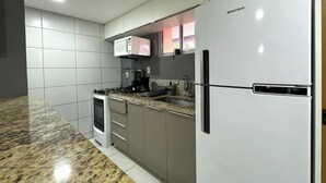 Una cocina moderna con estufa a gas, microondas, refrigerador y encimera de granito.