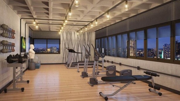 Een moderne fitnessruimte met diverse trainingsapparaten, grote ramen met uitzicht op de stad, en een hoge ruimte met zichtbare balken.