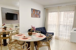 A modern dining area with a round table, beige chairs, and pink placemats.