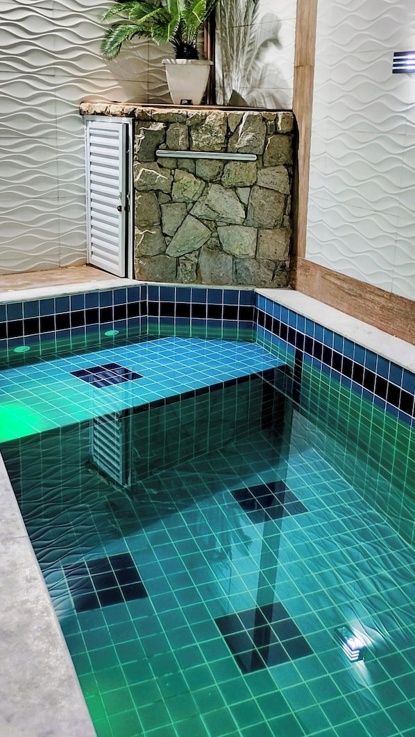 A swimming pool with a stone wall and tiled steps.