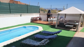 A backyard with a swimming pool, lounge chairs, a barbecue area, and a tent. - Noza Beach (Valle-Niza)